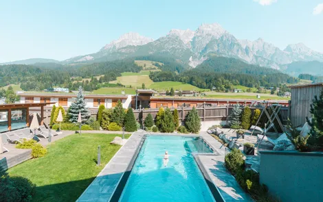 Sommerfeeling im Genießerhotel Riederalm Außenpool mit Liegestühlen vor Alpenkulisse in sonniger Hotelanlage